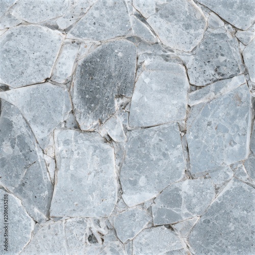 Close view of irregular gray stone paving with pale mortar joints, showing natural speckles, rough texture, and varied rock shapes.
