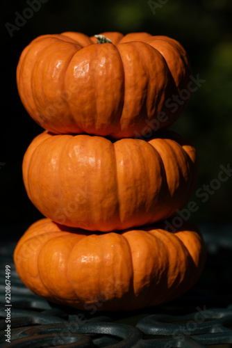 Close-up of three orange pumpkins stacked on top of each other on a metal grid