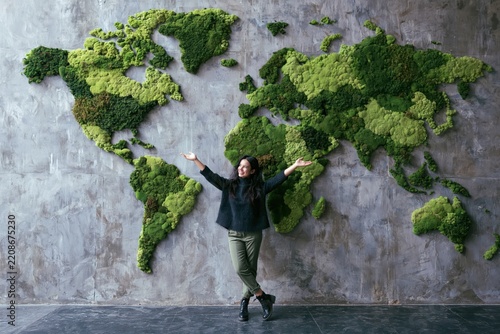Woman in front of a moss world map on a concrete wall