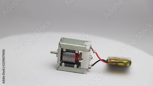 Small dc motor with visible parts in working condition while connected to mini lithium polymer battery
