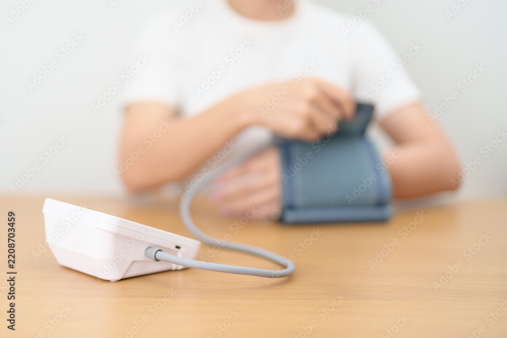 Fototapeta premium woman checking Blood pressure by Blood pressure monitor with Cuff. Systolic, SYS, Diastolic, DIA, Pulse, Hypertension, Hypotension, Heart rate, Cardiovascular Disease and May World hypertension day