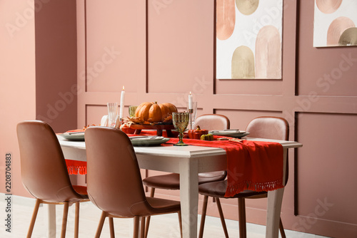 Thanksgiving dinner table setting, autumn home interior with pumpkin centerpi...