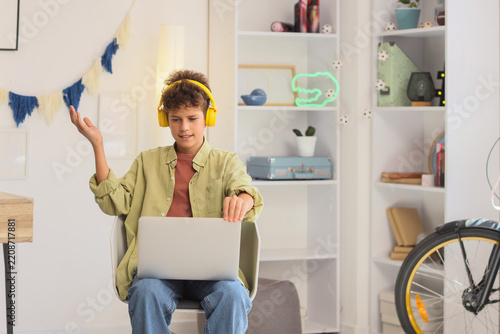 Remote learning and digital education, boy using laptop with headphones for o...