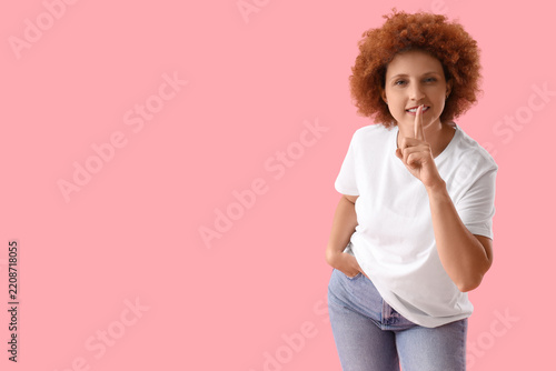Fotografie Confidentiality and privacy concept, woman with curly hair holding finger to lip