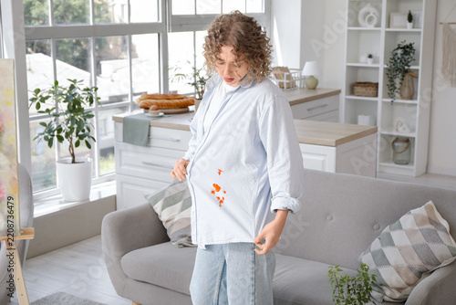 Fotografie Stain removal and laundry accident, woman looking at tomato sauce spill on her s
