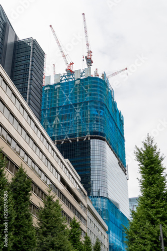 Completed modern office building standing next to a high-rise building under construction