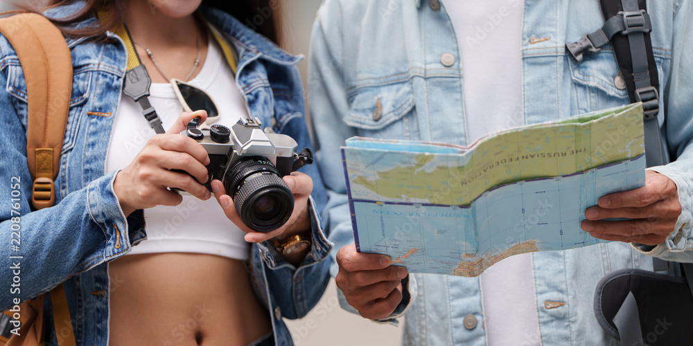 Obraz premium Asian tourists with map and camera for travel planning and navigation