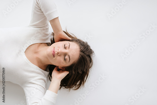 Young woman lying down relaxing with eyes closed on white background