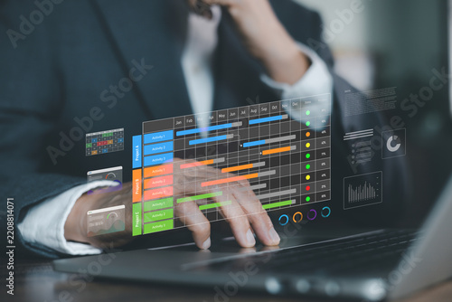 businessman typing on laptop with digital Gantt chart hologram overlay. Concept of project management software, workflow scheduling, business planning, and time tracking system.