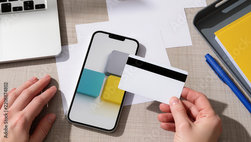 Business hands review a company card spending limit beside a smartphone and blank payment card, with expense papers, notebook and office supplies arranged on a sunlit desk