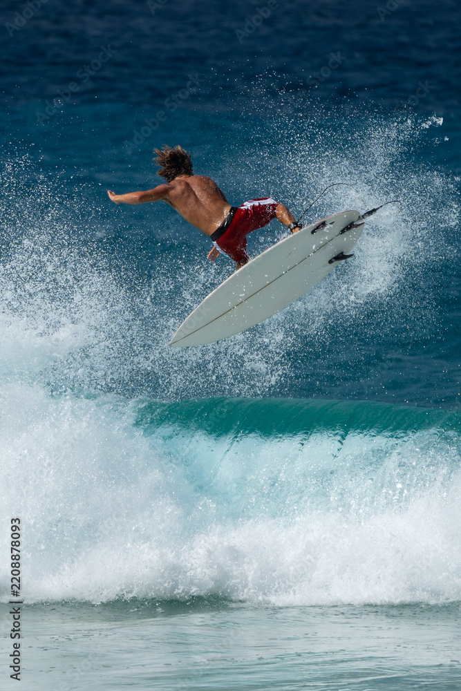 Obraz premium Surfer performing aerial maneuver above breaking ocean wave