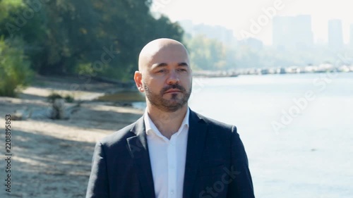 Confident bald businessman taking off sunglasses