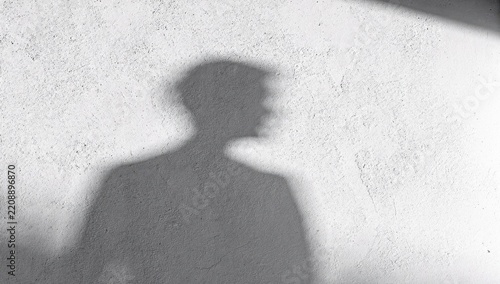 Human silhouette shadow cast on a white textured wall creating a dramatic effect
