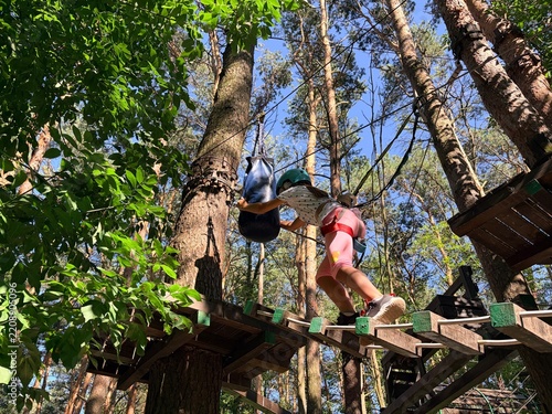 Active family leisure. A little girl navigates an obstacle course at a rope park. Climbing