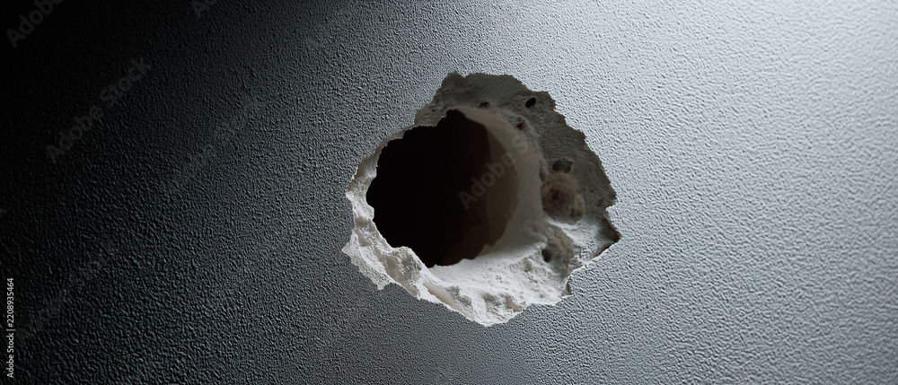 Fototapeta premium Large round broken hole damaged through dark textured plaster drywall inside an interior room space.