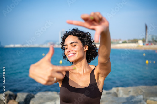 Woman framing beach view with finger frame