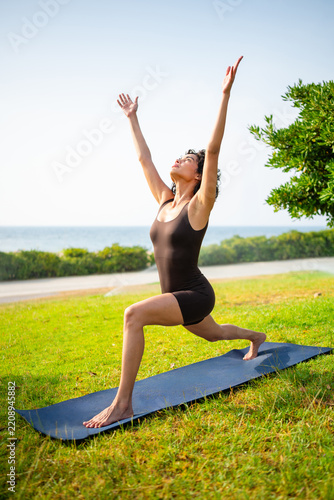 Woman practicing outdoor yoga warrior pose for wellness