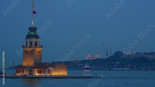 A breathtaking evening view of the historic Maiden's Tower illuminated on the Bosphorus strait with the iconic silhouette of Hagia Sophia and mosques in Istanbul