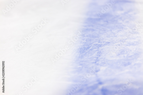 Close-up of scratched ice hockey rink with blue line, empty frozen surface with soft focus and copy space.