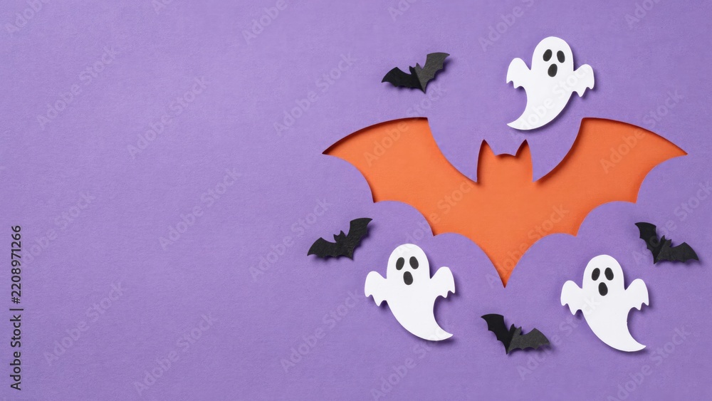 Fototapeta premium Halloween paper cutout flat lay with orange bat silhouette, white ghosts, and black bats on purple background