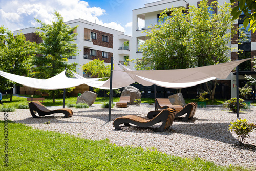 Obraz na plátně A stylish outdoor relaxation zone in a contemporary apartment complex featuring ergonomic wooden chaise lounges on a gravel surface