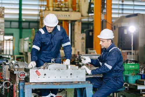 Professional engineer team worker training young man to service injection mold in die casting plant