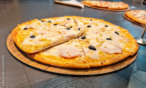 Hawaiian pizza or a version with ham, pineapple and olives on a thin base, with white or cheese sauce and mozzarella.