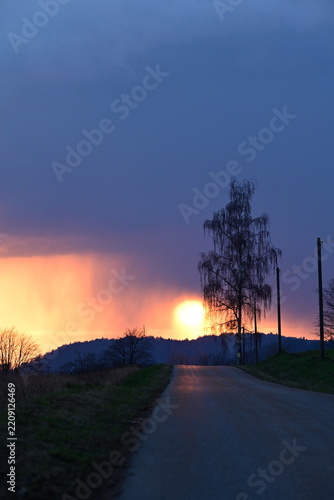 Dramatischer Sonnenuntergang kurz nach einem Gewitter auf einer Landstraße