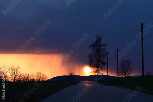 Dramatischer Sonnenuntergang kurz nach einem Gewitter auf einer Landstraße