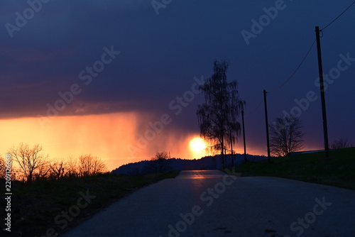 Dramatischer Sonnenuntergang kurz nach einem Gewitter auf einer Landstraße