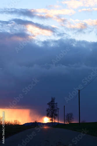 Dramatischer Sonnenuntergang kurz nach einem Gewitter auf einer Landstraße