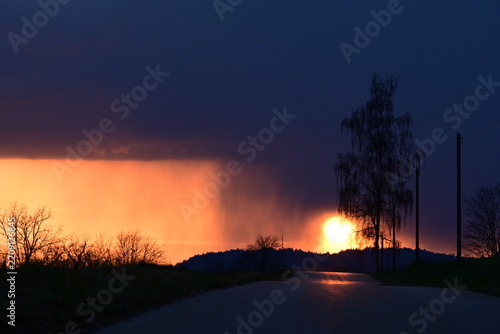 Dramatischer Sonnenuntergang kurz nach einem Gewitter auf einer Landstraße