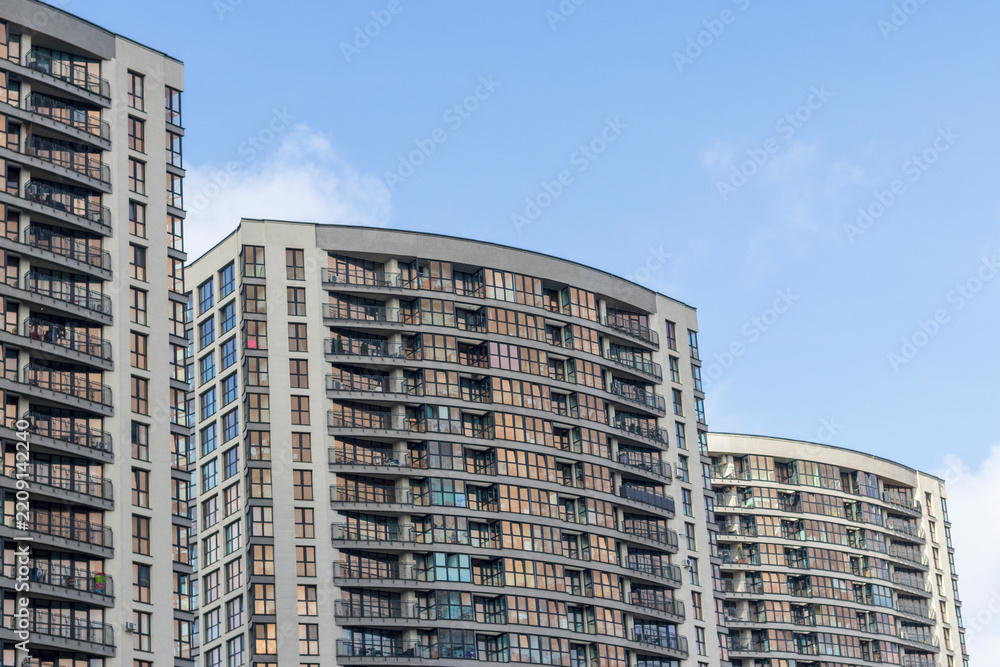 Fototapeta premium Modern curved residential apartment complexes against a blue sky. City