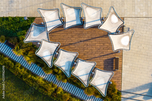 Aerial view of modern tensile fabric shades arranged in a circular pattern over a wooden deck in a park in Plock, Mazowieckie Voivodeship, Poland.
