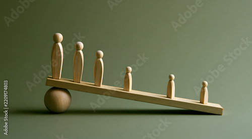 Stylized human figures made of wood arranged on an inclining board symbolizing social disparities and economic divide.