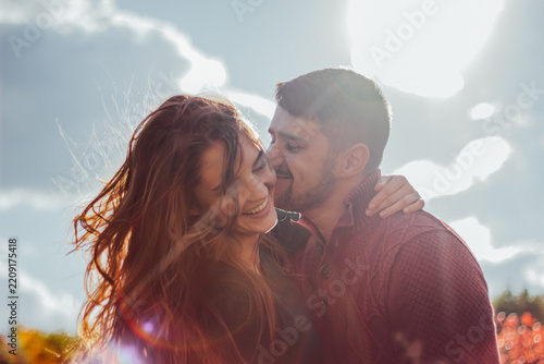 Smiling couple embracing outdoors under sunlight