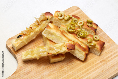 Italian focaccia with onion and olive topping on board