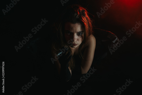 Fotografie A young woman looks directly at the camera in a dramatic low-key portrait
