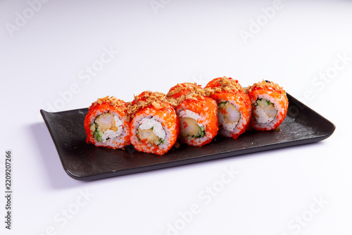 Five sushi rolls with shrimp cucumber and orange roe on black plate