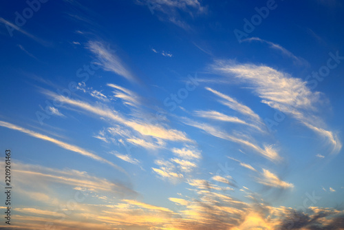 Golden sunset clouds floating in blue sky at dusk 