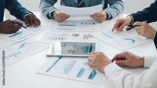 Diverse business team analyzing financial charts during a corporate meeting with a tablet