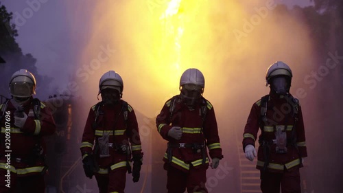Firefighters walking together through thick smoke and bright fire