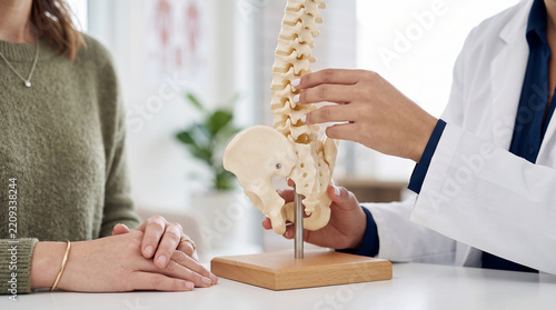 Close up of a medical professional explaining spinal anatomy to a patient using a bone model perfect for chiropractic and orthopedic care concepts