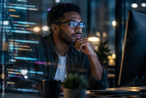 Man Working on Computer With Code Displayed in a Tech Office During Evening H...