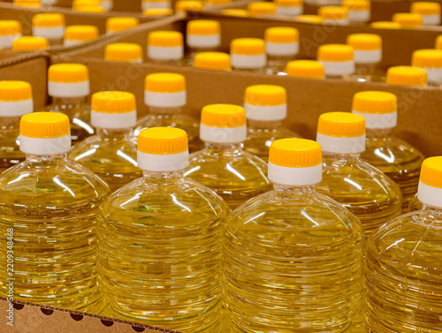 Bottles of sunflower oil with a distinct yellow color stand in cardboard boxes on grocery store counters, showing how edible vegetable oil is presented for sale