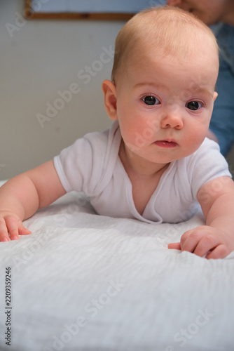 Cute little baby lie down on bed and look at camera with happy mood