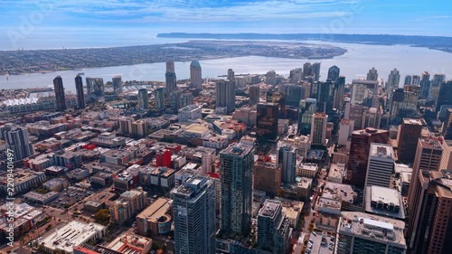 San Diego city blocks and waterfront towers above the bay. An elevated view shows streets and buildings extending toward San Diego Bay and its curved shoreline.