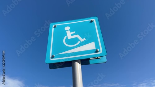 Right-to-left panning shot from disabled parking sign to wheelchair ramp accessibility sign.