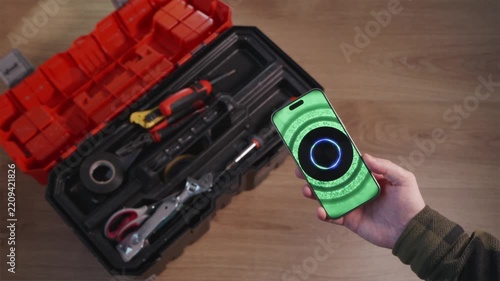 Hand holding smartphone with AI assistant near toolbox while selecting tool