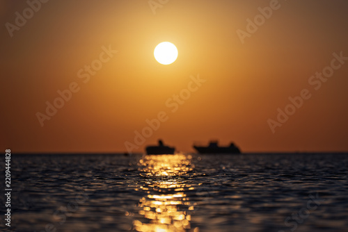 First rays of the rising sun appearing over the ocean horizon at dawn.